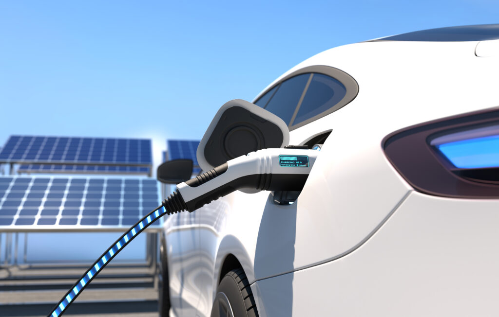 Electric car charging at a station with solar panels in the background, symbolizing clean energy and sustainable transportation.