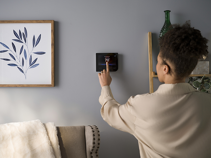 homeowner turning on smart thermostat 